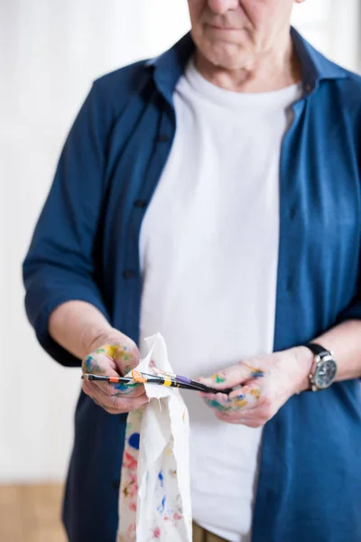 Senior man cleaning paint brushes — Stock Photo, Image