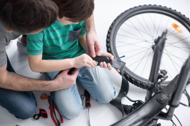father and son repairing bicycle tire