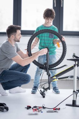 father and son repairing bicycle  clipart