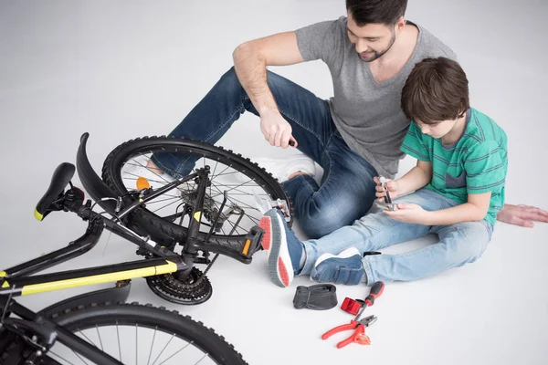 Padre e hijo reparando bicicleta — Foto de Stock