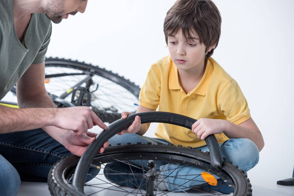 Сын и отец ремонтируют велосипед
 