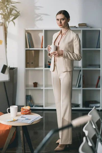 Молода бізнес-леді тримає чашку — Безкоштовне стокове фото
