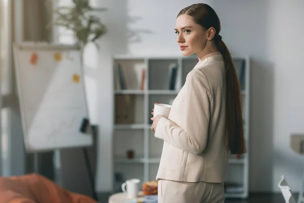 Jeune femme d'affaires tenant tasse — Photo