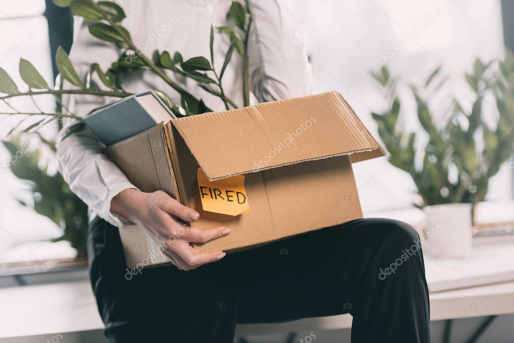 Fired businesswoman holding box 