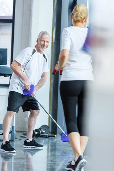Man with barbell and sportswoman in gym — Free Stock Photo
