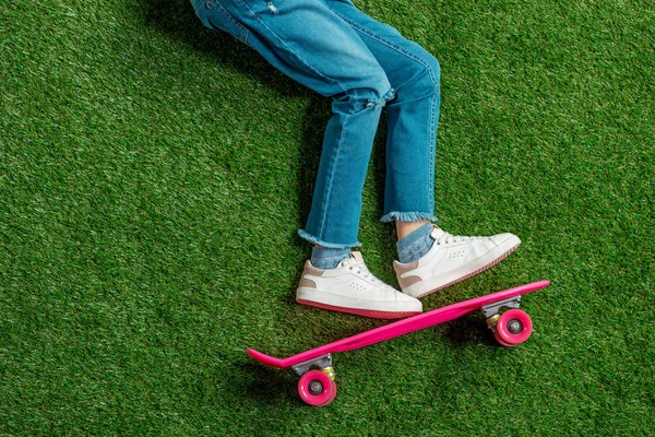 Menina com skate deitado na grama — Fotografia de Stock