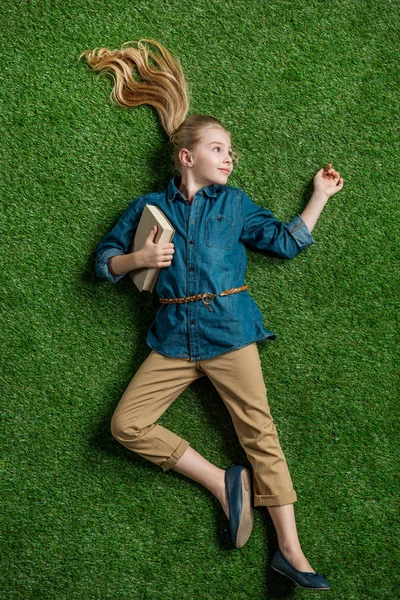 Mädchen mit Buch auf Gras liegend — Stockfoto