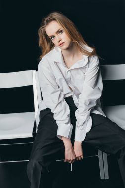 Woman in male shirt sitting on chairs