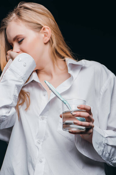 Молодая женщина в мужской рубашке зевает
