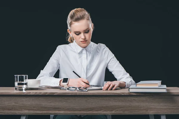 Woman sitting at table and making notes — Stock Photo, Image