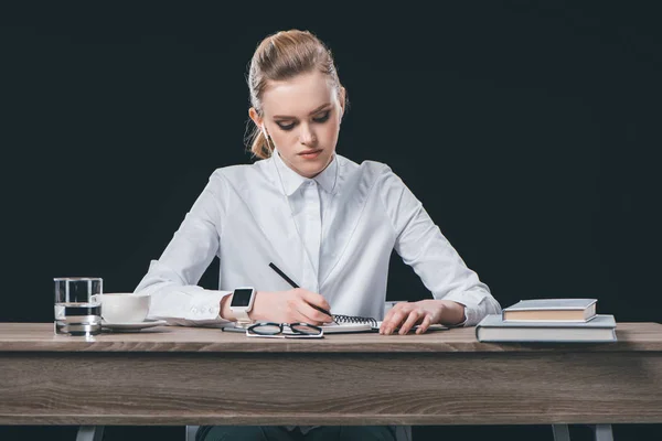 Femme assise à table et prenant des notes — Photo