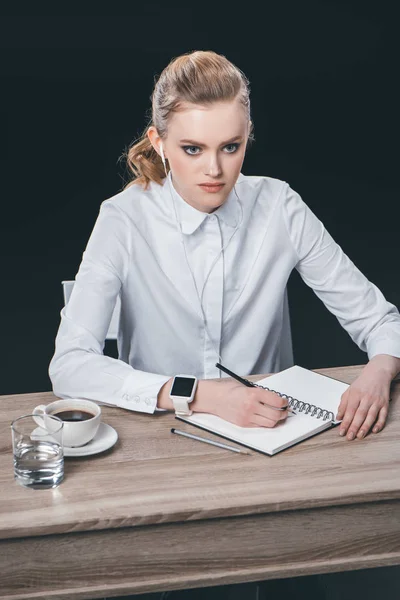 Mulher sentada à mesa e fazendo anotações — Fotografia de Stock