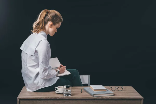 Woman sitting on table and making notes — Stock Photo, Image
