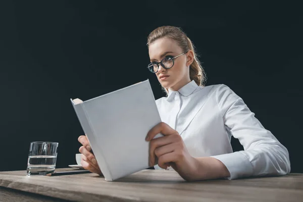 Mujer sentada en la mesa con el libro en las manos — Foto de Stock