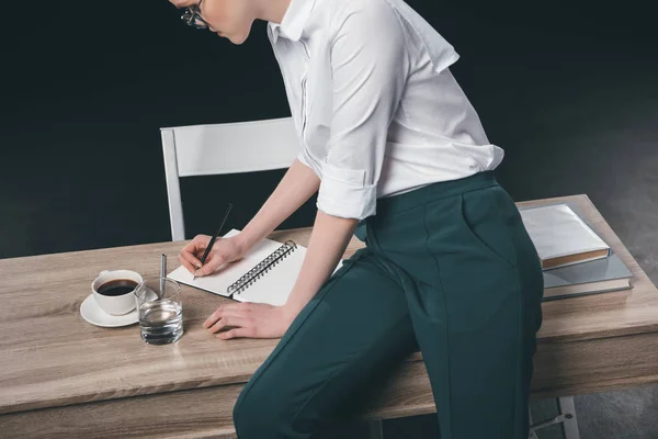 Mulher em traje escrevendo notas no bloco de notas — Fotografia de Stock