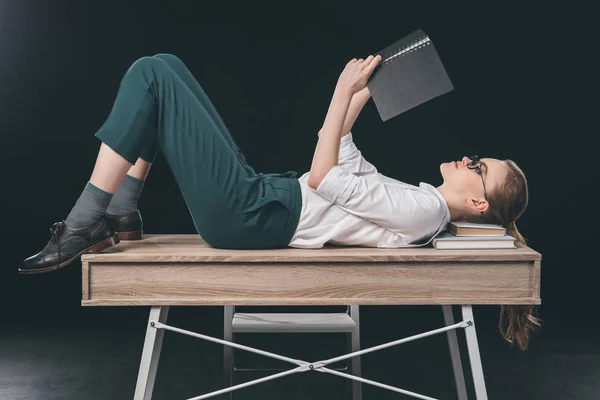 Frau liegt auf Tisch und liest Notizen — Stockfoto