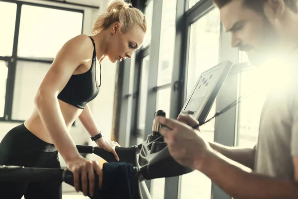 Blonde woman workout on treadmill and trainer with timer, side view — Stock Photo, Image