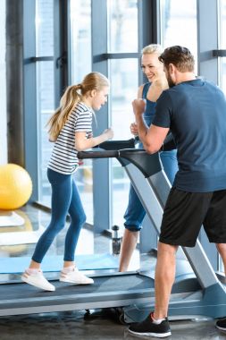 Parents supporting daughter workout on treadmill clipart