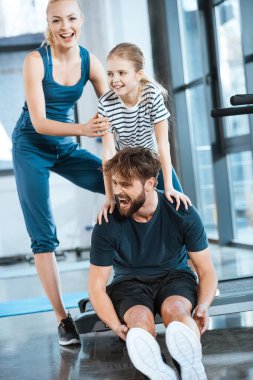 Spor salonunda koşu bandı üzerinde oturan kız kucaklama yorgun baba kadınla
