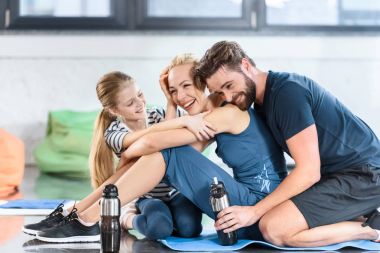 Happy family resting after workout at gym clipart