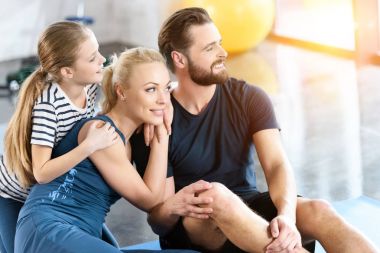 Spor salonunda oturan mutlu bir aile portresi