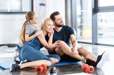 Portrait of happy family sitting on mat at gym