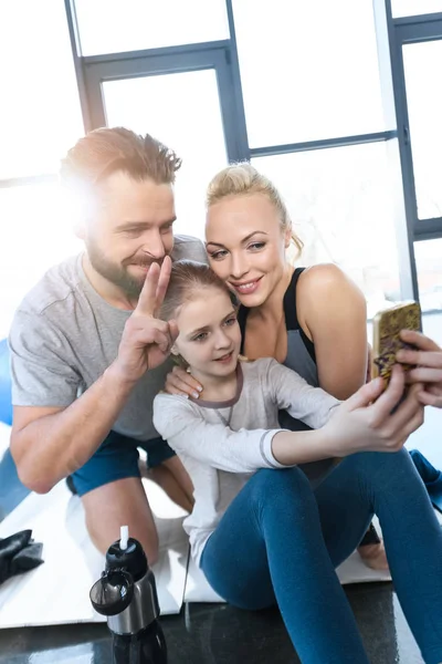 Девушка фотографируется с родителями в фитнес-центре — стоковое фото