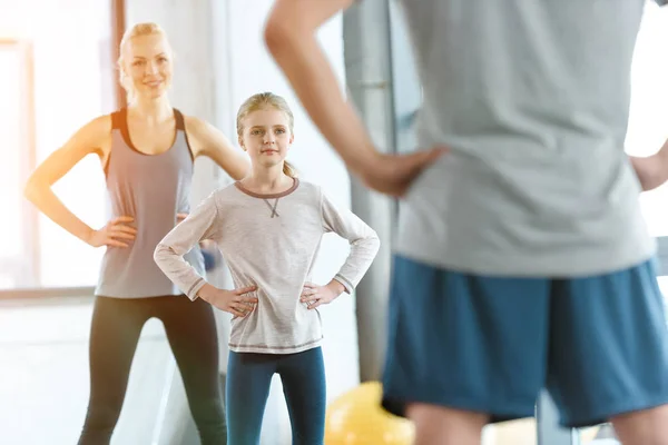 Young woman and cute girl exercising with coach at fitness studio — Stock Photo, Image