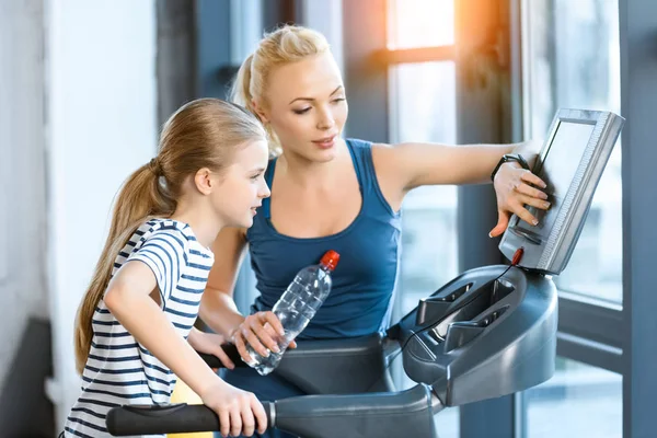 Vrouw trainer met klein meisje workout op een loopband — Stockfoto