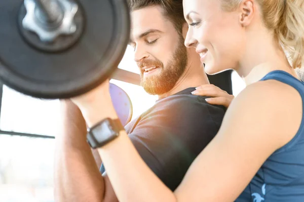 Loving couple exercising together with barbell at gym — Stock Photo, Image