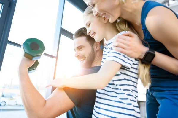 Happy young and girl looking guy workout with dumbbell — Stock Photo, Image