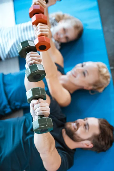 Família feliz exercitando com halteres no estúdio de fitness — Fotografia de Stock
