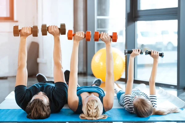 Família feliz exercitando com halteres no estúdio de fitness — Fotografia de Stock