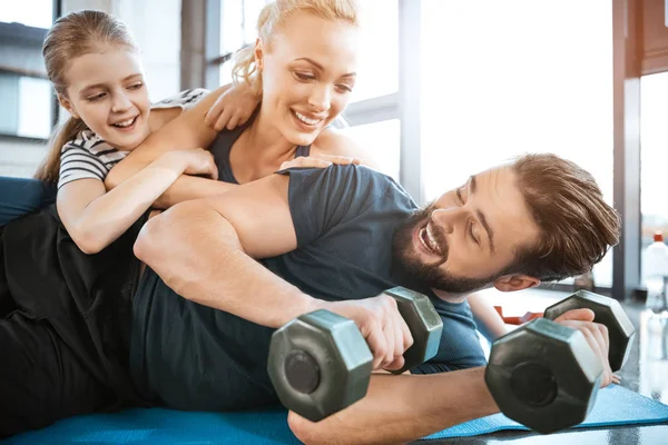 Lyckliga familjen ha roligt på gymmet, man holding hantlar — Stockfoto