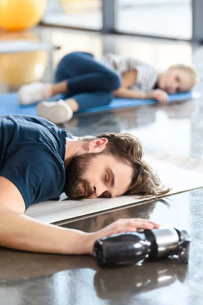 Hombre dormido cansado acostado en la estera en el gimnasio — Foto de Stock