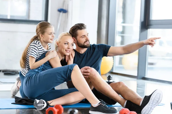 Porträtt av lycklig familj sitter på matta på gym — Stockfoto