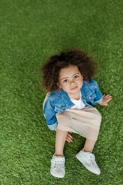 Lockiges Mädchen ruht sich auf Rasen aus — Stockfoto