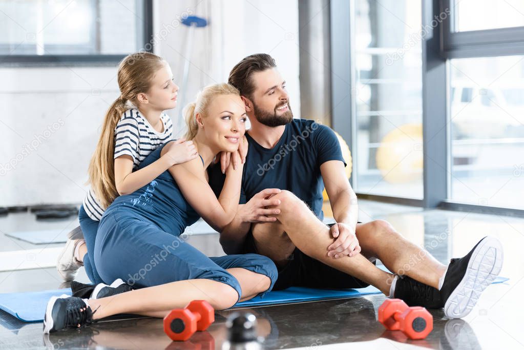 Portrait of happy family sitting on mat at gym