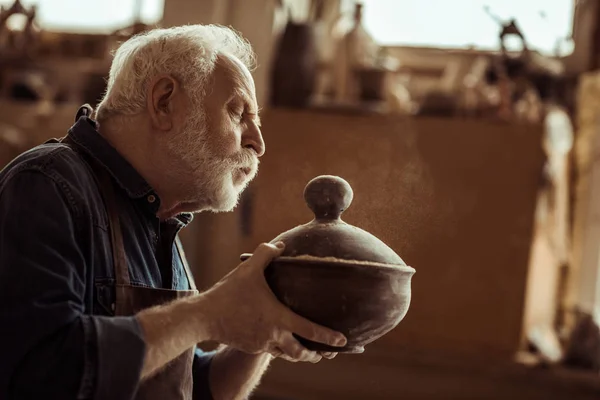 Starszy potter w fartuch, badając miski ceramiczne o warsztatów — Zdjęcie stockowe