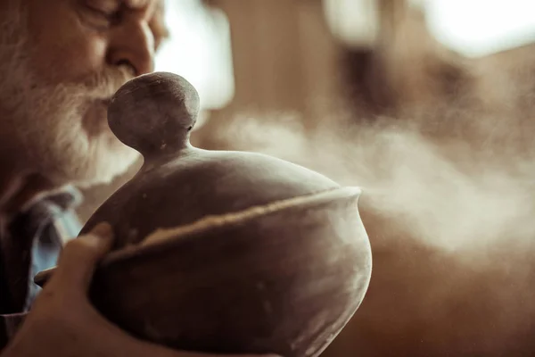 Close up of senior potter in apron examining ceramic bowl at workshop — Stock Photo, Image