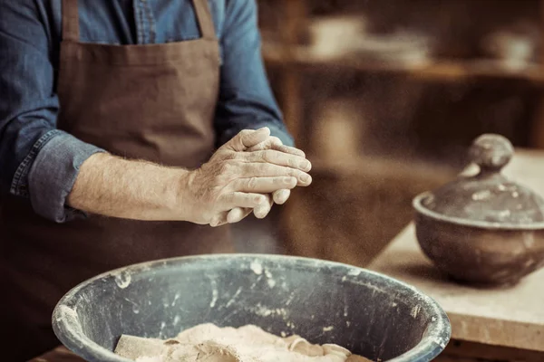 Nahaufnahme männlicher Töpferhände, die Ton aus einer Schüssel nehmen — Stockfoto