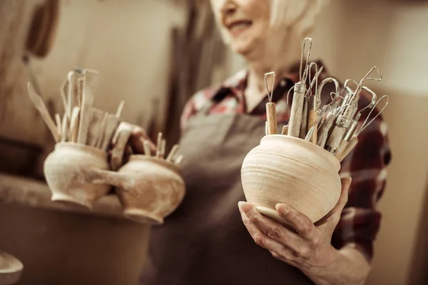 Старшая женщина держит миски с керамическими инструментами на семинаре — стоковое фото