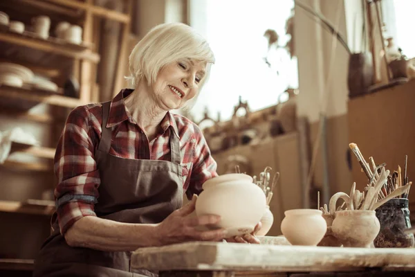 Potter kobieta siedzi przy stole i zbadanie miski ceramiczne o warsztatów — Darmowe zdjęcie stockowe