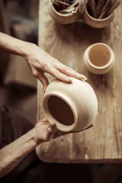 Nahaufnahme weiblicher Hände bei der Untersuchung von Keramikschalen in der Werkstatt — kostenloses Stockfoto
