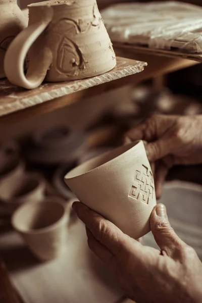 Primer plano de la mano masculina del alfarero examinando taza de arcilla — Foto de Stock