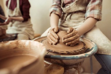 Close up of child hands working on pottery wheel at workshop clipart