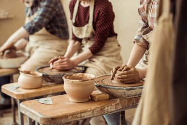 Cropped image of grandmother and grandfather with granddaughter making pottery at workshop clipart