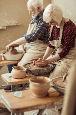 Grandmother and grandfather making pottery at workshop clipart