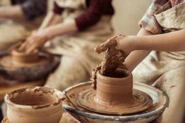 Close up of child hands working on pottery wheel at workshop clipart