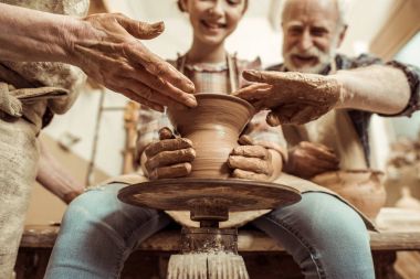 Grandmother and grandfather with granddaughter making pottery at workshop clipart